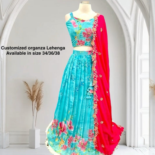 Turn heads with this stunning customized organza lehenga set. The vibrant turquoise blue lehenga with floral detailing pairs beautifully with a hot pink embroidered dupatta. Perfect for festive occasions, weddings. Available in size 34/36/38.