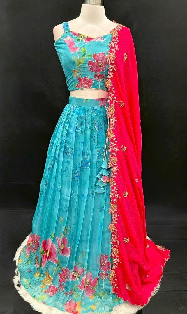 Turn heads with this stunning customized organza lehenga set. The vibrant turquoise blue lehenga with floral detailing pairs beautifully with a hot pink embroidered dupatta. Perfect for festive occasions, weddings. Available in size 34/36/38.