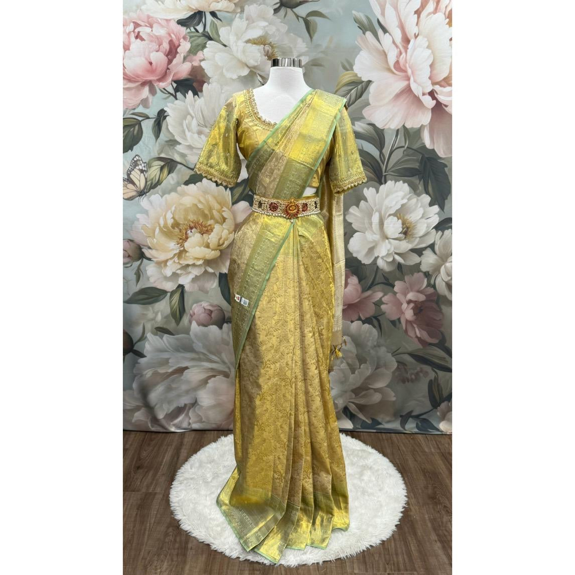 Pure Kanchi Pattu Silk mark certified Saree in shimmering gold with a subtle green border. Paired with an exquisite handcrafted Maggam work blouse. Available in size 40 to 44.