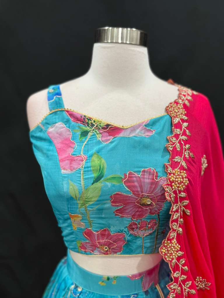 Turn heads with this stunning customized organza lehenga set. The vibrant turquoise blue lehenga with floral detailing pairs beautifully with a hot pink embroidered dupatta. Perfect for festive occasions, weddings. Available in size 34/36/38.